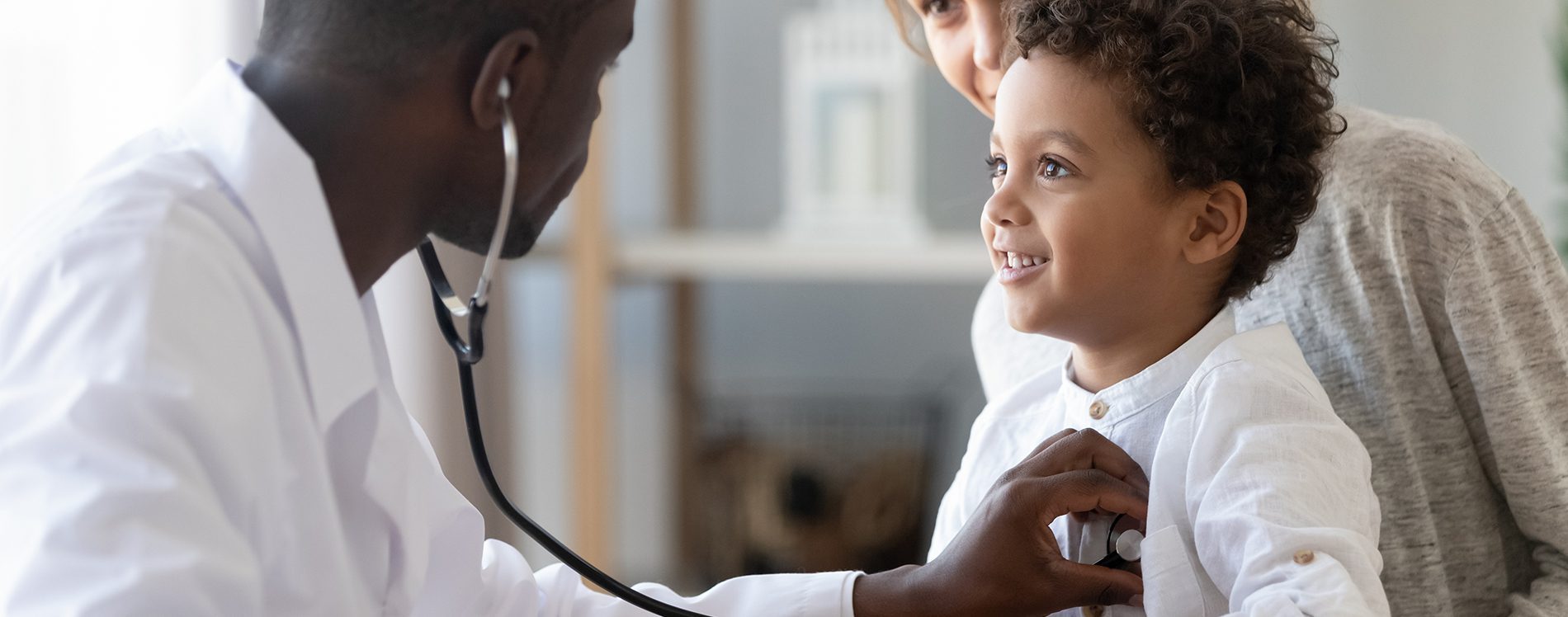 Black doctor checking a small child with the stethoscope.