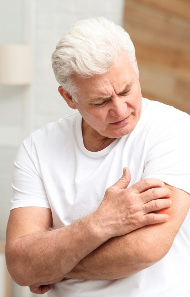 Older man scratching arm.