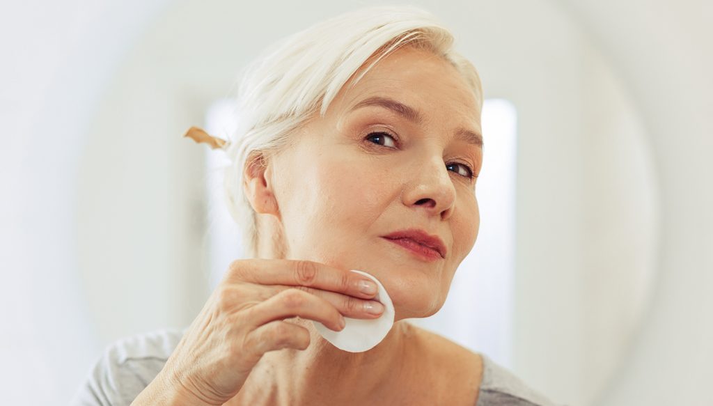 Older woman cleaning her face.
