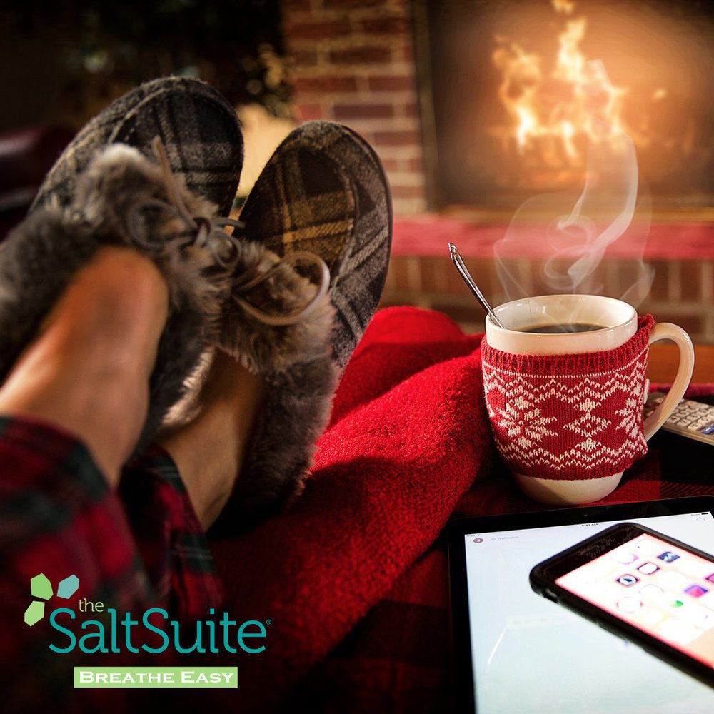 Person relaxing by fireplace and enjoying a cup of coffee during Christmas time.