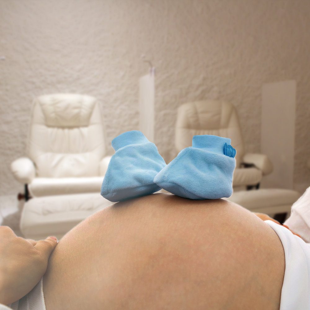 Blue booties on a pregnant belly while enjoying a salt session.