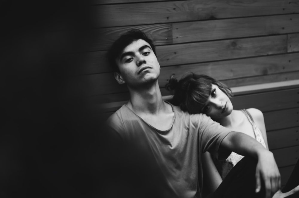 Young man relaxed and laying back as a young girl leans on his shoulder.