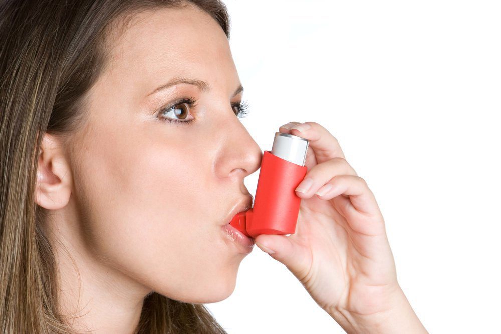 Side view of a woman using an inhaler.