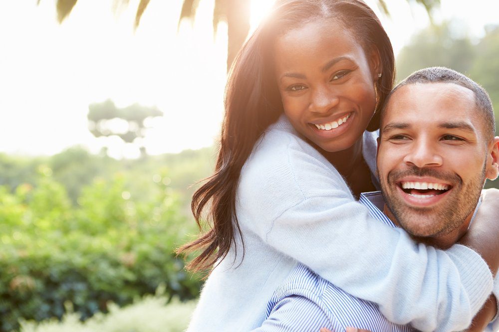 Young beautiful black women on handsome man's back.