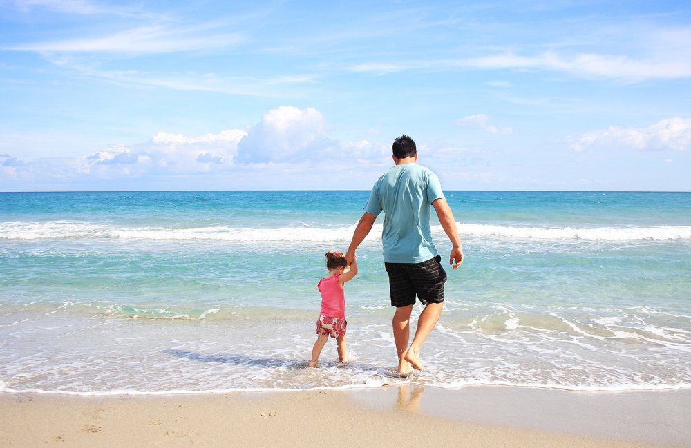 Father and daughter walking near the shore.