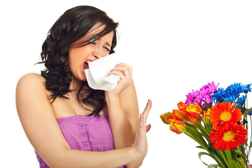 Young pretty women sneezing and rejecting flowers given to her due to allergies.