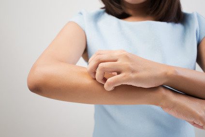Close up of a woman scratching her arm.