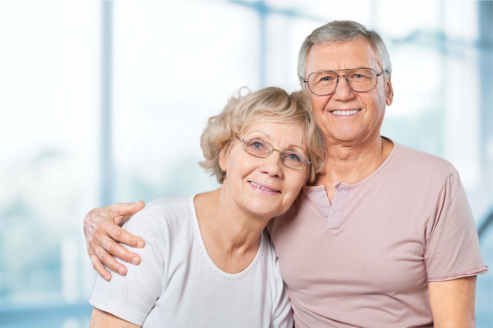 Older white couple smiling as the hug each other.
