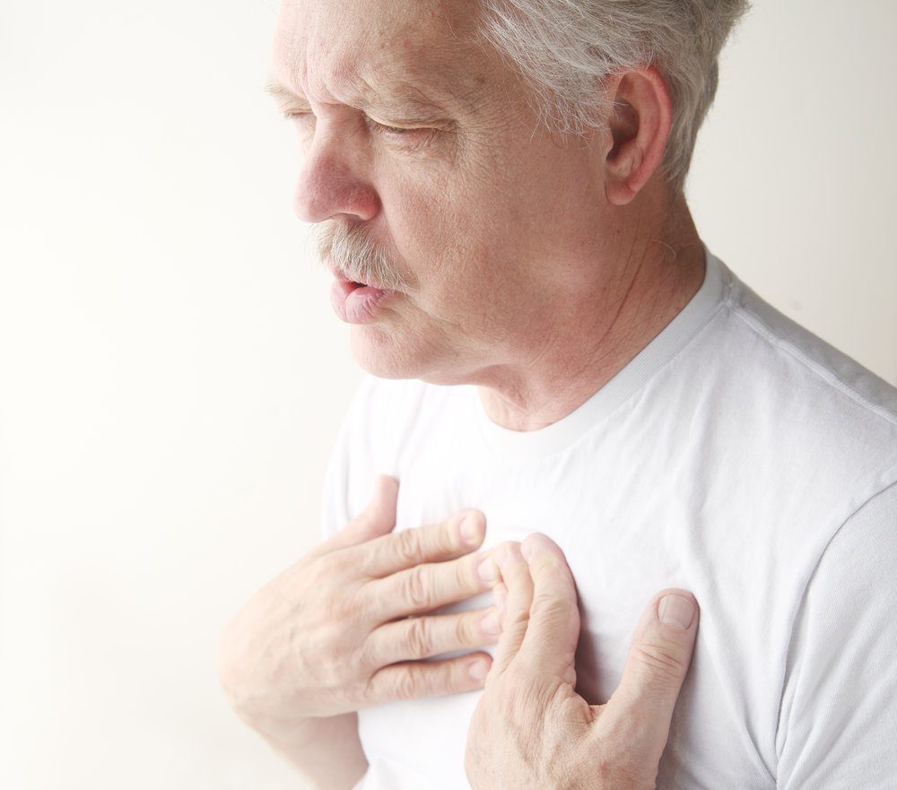 Older man with his hands on his chest and exhaling.