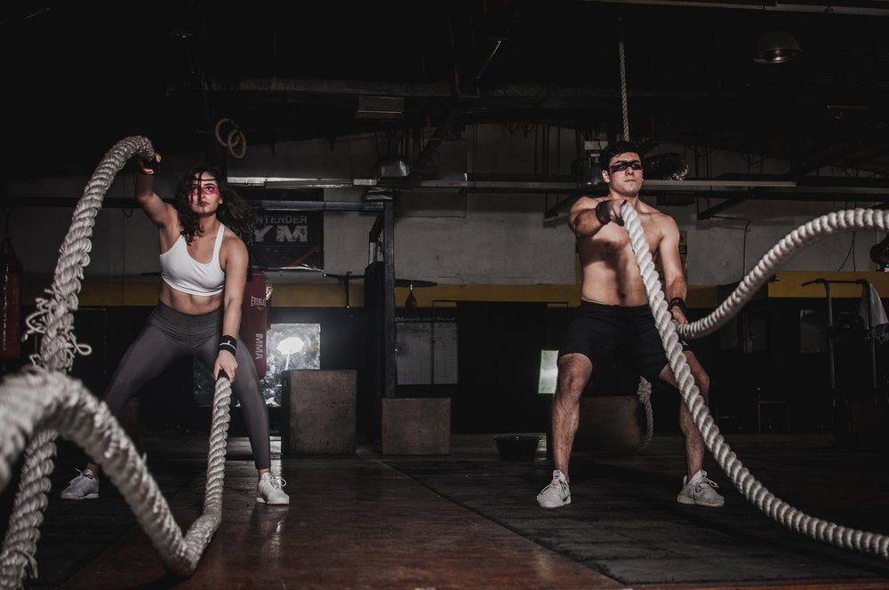 Man and woman doing crossfit battle ropes.