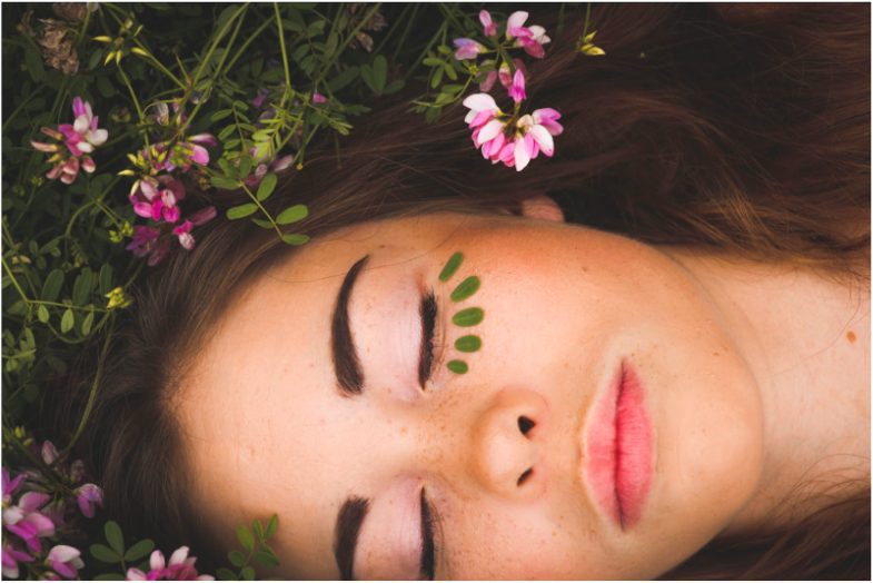 Young pretty woman laying on bed of flowers.
