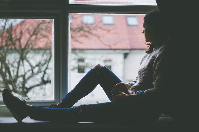 Woman sitting by window as she looks outside.
